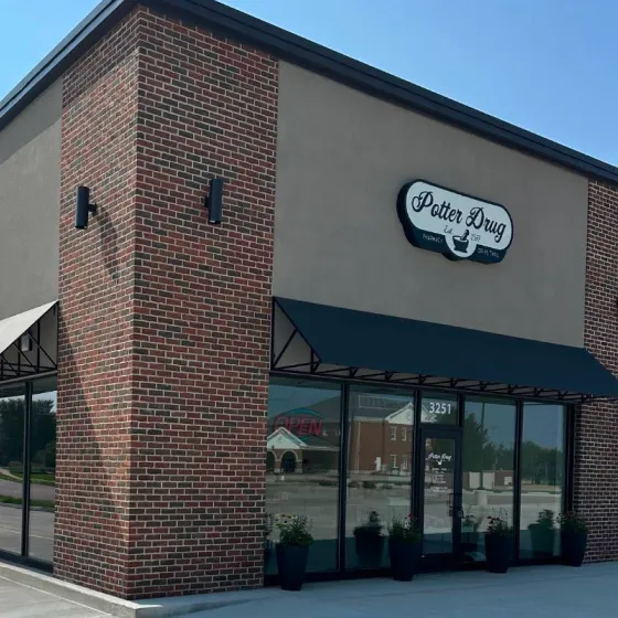 A brick building with black awnings and a sign reading "Potter Drug" above the entrance.